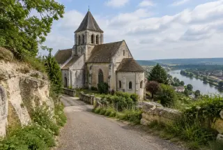 Église prieurale en pierre claire de Saint-Leu-d’Esserent au bord d’un chemin calcaire, avec la vallée de l’Oise en arrière-plan.